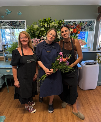 Helen, Astrid and Gemma, the florists at The Petal Boutique in Weyhill, together in the shop with a hand-tied bouquet.