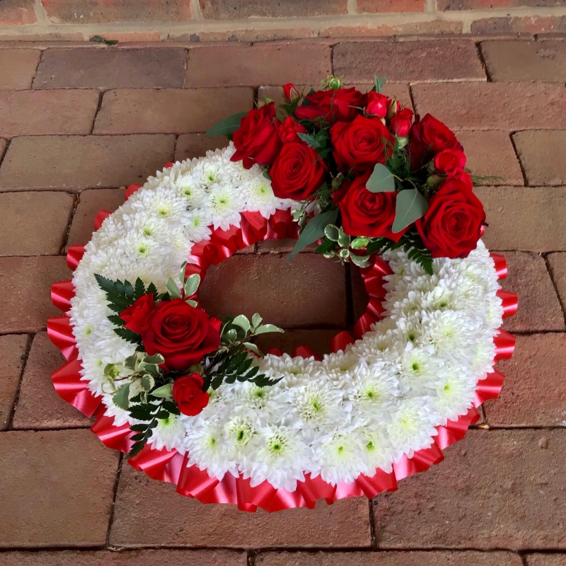 Traditional funeral wreath of red roses and white seasonal flowers