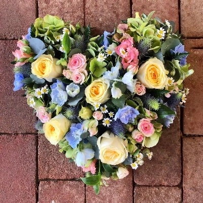 Loose flower heart tribute of mixed fresh blooms in natural style with a foliage edge