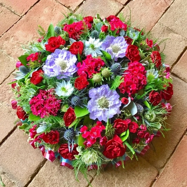 Florist choice posy pad of mixed seasonal flowers set in floral foam