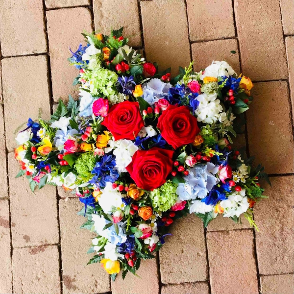 Star shaped funeral tribute massed in bright flowers with ribbon edge