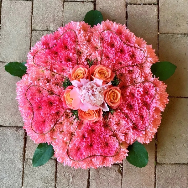 Wild rose funeral tribute of pink roses and seasonal flowers