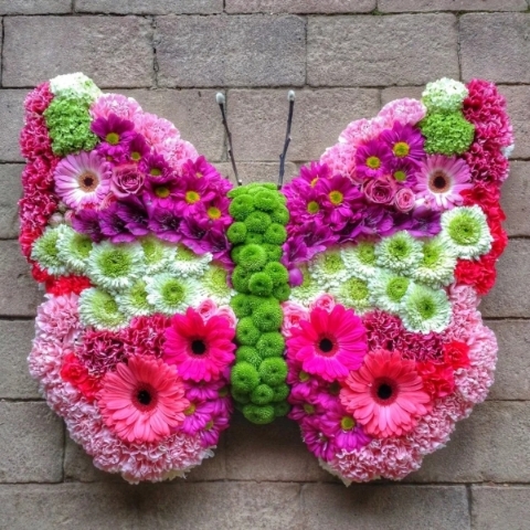 Butterfly shaped funeral tribute in soft coloured flowers with defined wing edges