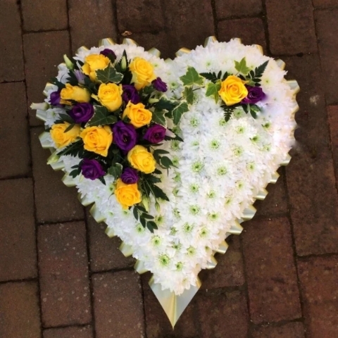 Solid heart funeral tribute massed in red and pink flowers